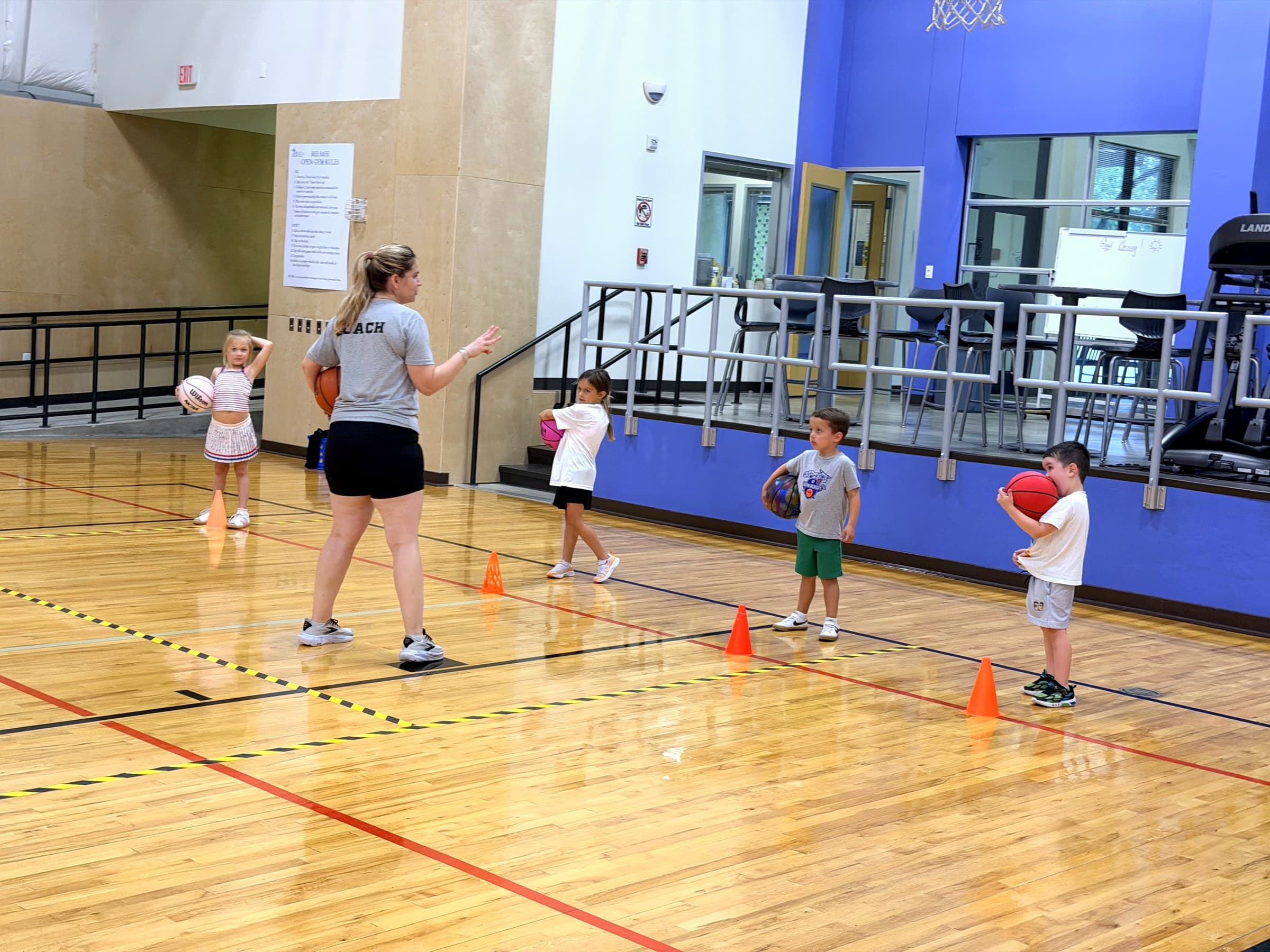 A Wildcats coach teaching a line of young players during a ball-handling drill